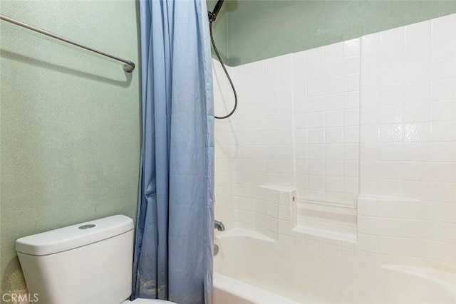 bathroom featuring toilet and shower / bath combination with curtain