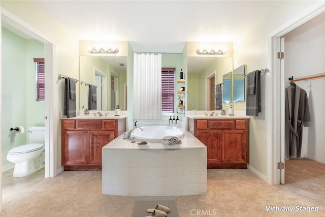 bathroom featuring tiled bath, toilet, and vanity