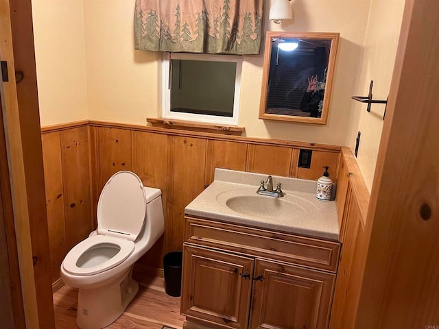 bathroom with vanity, wood walls, toilet, and wood-type flooring