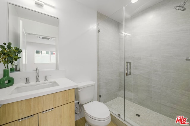 bathroom featuring an enclosed shower, vanity, and toilet