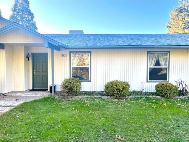 property entrance with a yard and roof with shingles