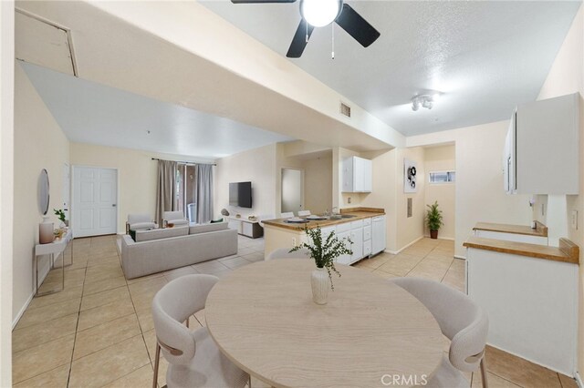 dining space with a textured ceiling, ceiling fan, and light tile patterned floors