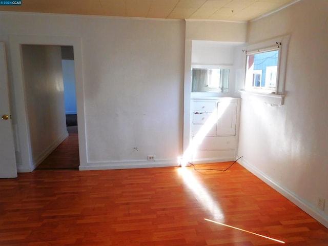 empty room featuring hardwood / wood-style flooring and crown molding