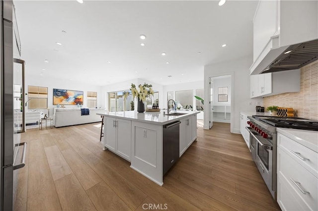 kitchen featuring white cabinetry, light hardwood / wood-style flooring, an island with sink, and stainless steel appliances