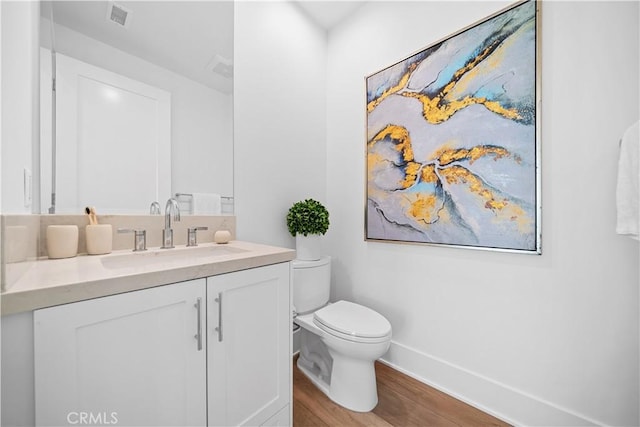 bathroom with wood-type flooring, vanity, and toilet