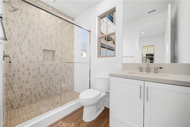 bathroom with hardwood / wood-style flooring, toilet, an enclosed shower, and vanity