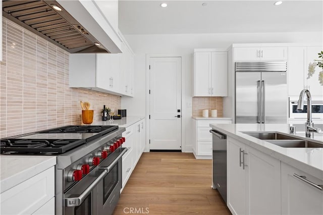 kitchen featuring light wood-type flooring, custom exhaust hood, sink, high quality appliances, and white cabinets