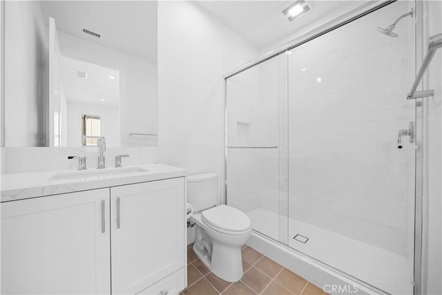 bathroom with tile patterned flooring, vanity, toilet, and walk in shower