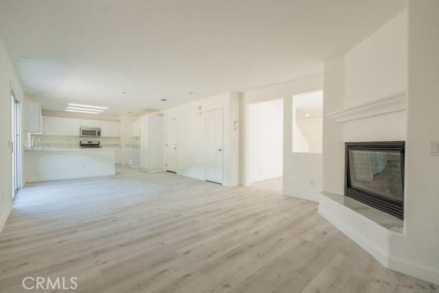 unfurnished living room with sink and light hardwood / wood-style flooring