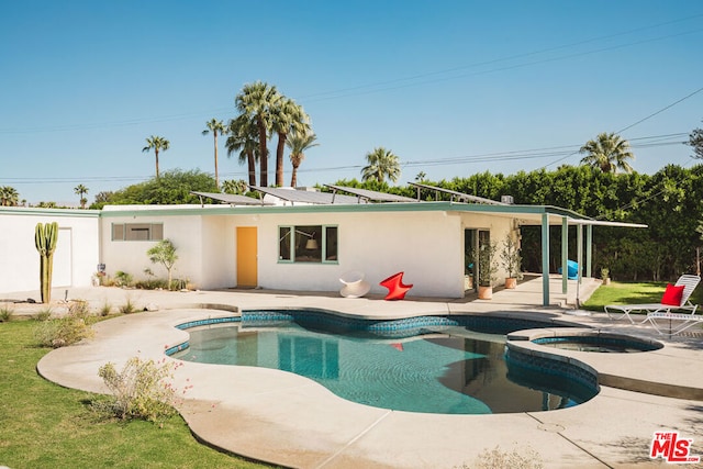 back of property with solar panels, a swimming pool with hot tub, and a patio area