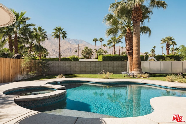 view of swimming pool with a mountain view and an in ground hot tub