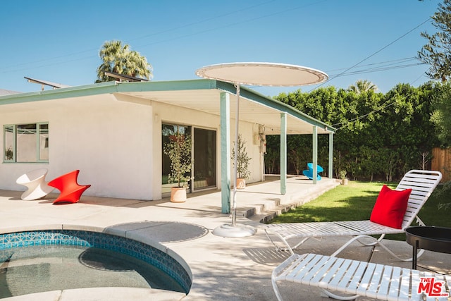 rear view of property featuring a lawn, a patio area, and a swimming pool