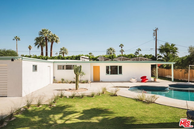 rear view of property featuring a yard, a patio, and a pool with hot tub