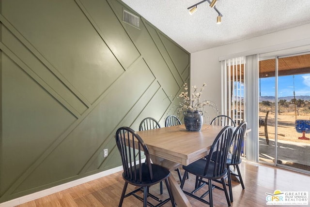 dining area with light hardwood / wood-style floors and a textured ceiling