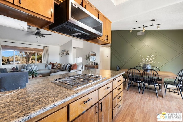 kitchen with light hardwood / wood-style floors, stainless steel gas stovetop, ceiling fan, and vaulted ceiling