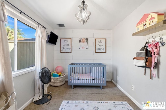 bedroom featuring a notable chandelier, carpet floors, and a crib