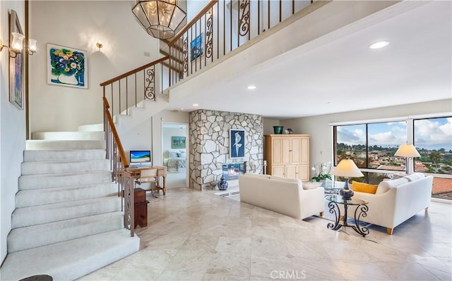 living room with a stone fireplace and a towering ceiling