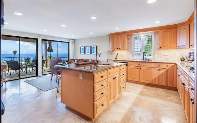 kitchen featuring an island with sink, a water view, sink, and a kitchen bar