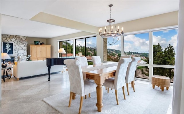 dining space featuring an inviting chandelier and a stone fireplace