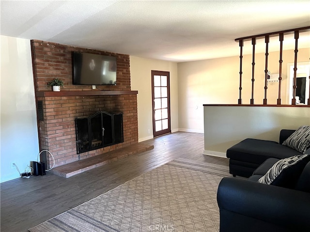 living room with a textured ceiling, a brick fireplace, and wood-type flooring