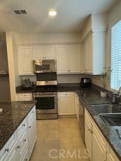 kitchen featuring white cabinets, sink, stainless steel appliances, and dark stone countertops