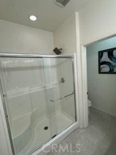 bathroom with a shower with shower door and toilet