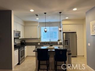 kitchen with pendant lighting, white cabinets, a breakfast bar area, a kitchen island, and stainless steel appliances