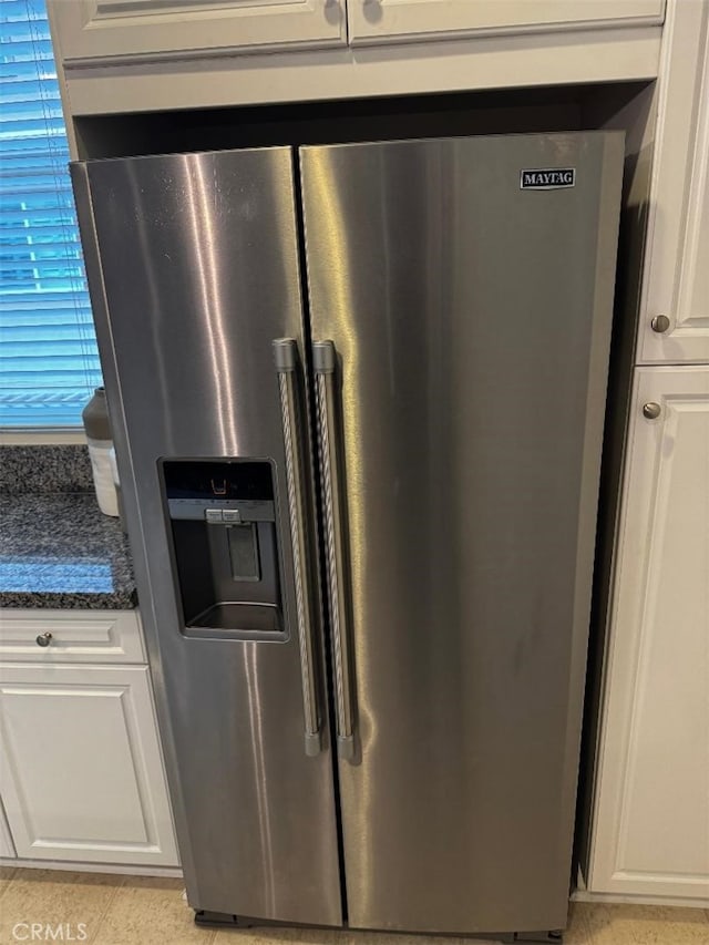 room details with white cabinets, stainless steel fridge, and dark stone countertops