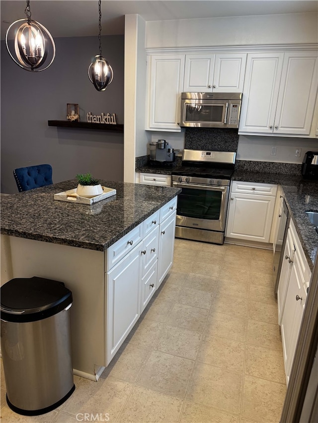 kitchen with stainless steel appliances, decorative light fixtures, dark stone countertops, white cabinets, and a center island