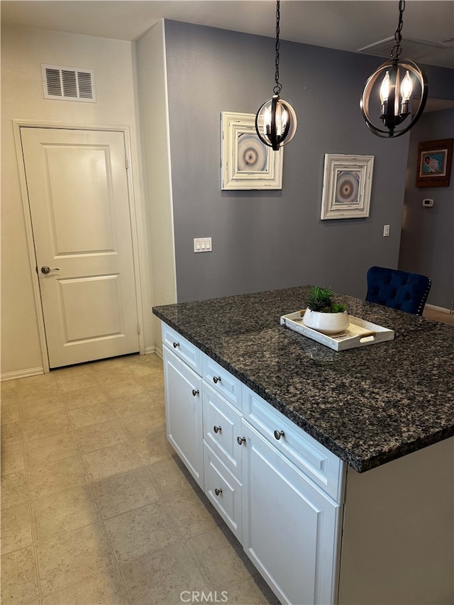 kitchen with dark stone countertops, white cabinets, decorative light fixtures, and an inviting chandelier