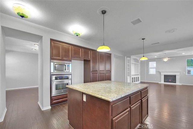 kitchen with pendant lighting, dark hardwood / wood-style flooring, stainless steel appliances, and a kitchen island