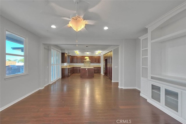 unfurnished living room featuring dark hardwood / wood-style flooring, built in features, and ceiling fan