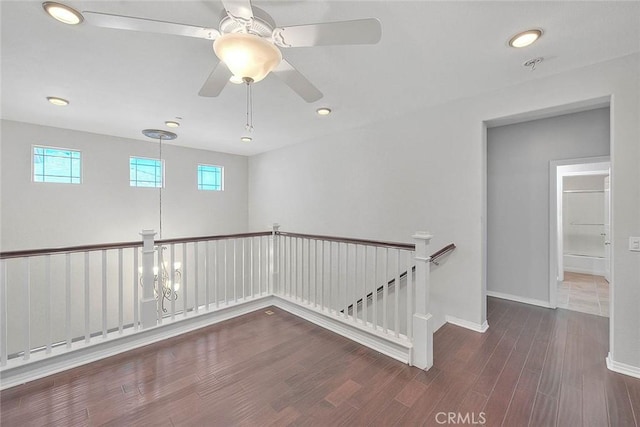 unfurnished room featuring ceiling fan with notable chandelier and dark hardwood / wood-style flooring