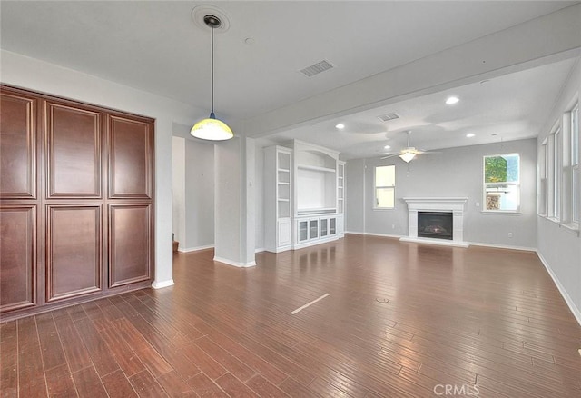 unfurnished living room featuring dark hardwood / wood-style flooring, built in features, and ceiling fan