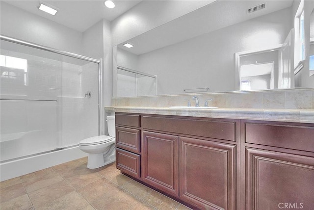 bathroom featuring vanity, a shower with shower door, and toilet