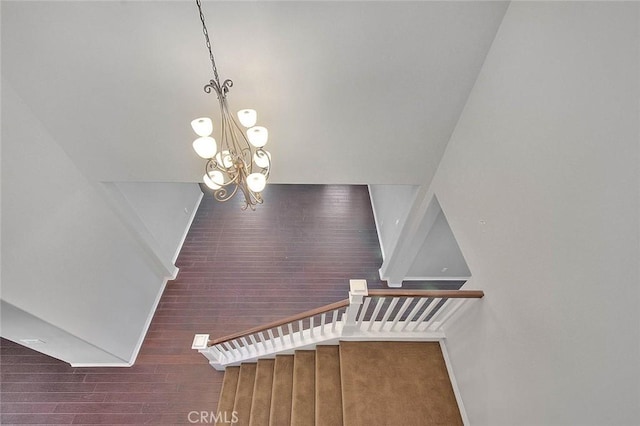 stairs featuring hardwood / wood-style floors and an inviting chandelier