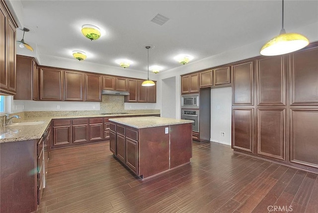 kitchen with a center island, dark wood-type flooring, sink, hanging light fixtures, and appliances with stainless steel finishes