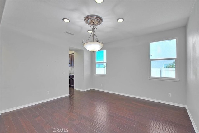 spare room with plenty of natural light and dark hardwood / wood-style floors