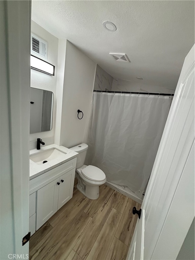 bathroom featuring hardwood / wood-style floors, a textured ceiling, toilet, vanity, and a shower with shower curtain