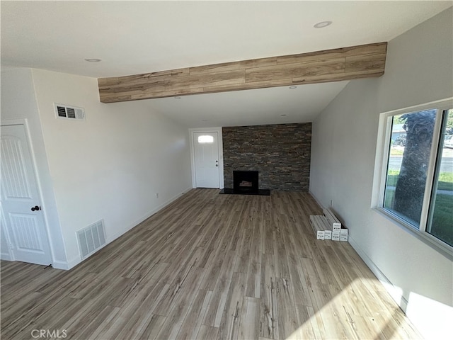 unfurnished living room with vaulted ceiling with beams, a fireplace, and light wood-type flooring