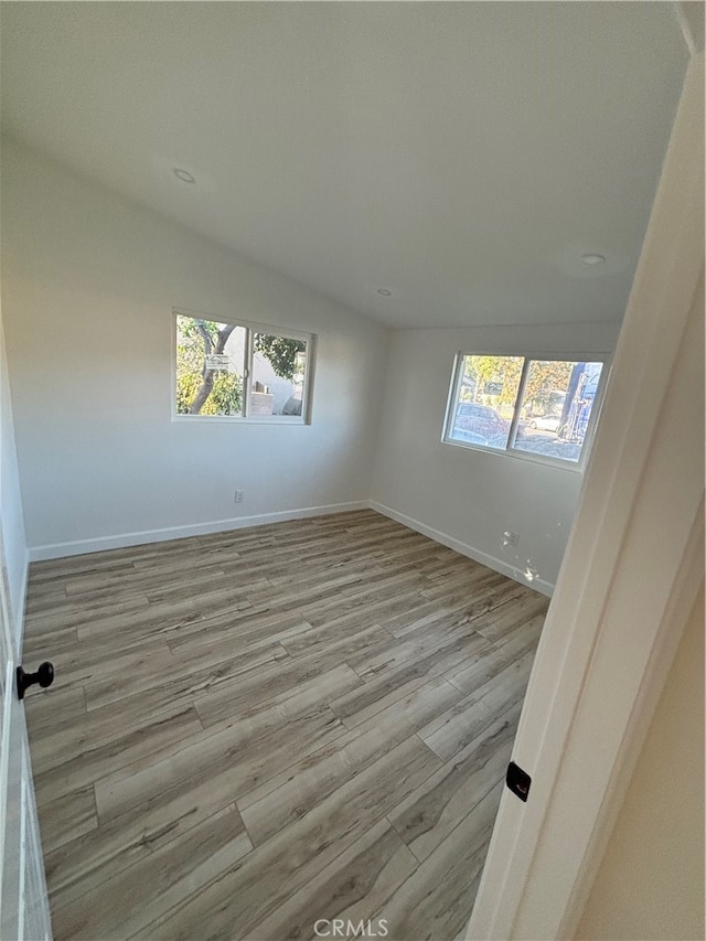 empty room featuring vaulted ceiling and light hardwood / wood-style floors