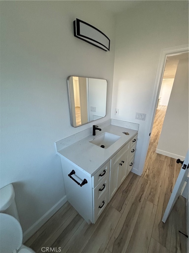 bathroom featuring vanity, wood-type flooring, and toilet