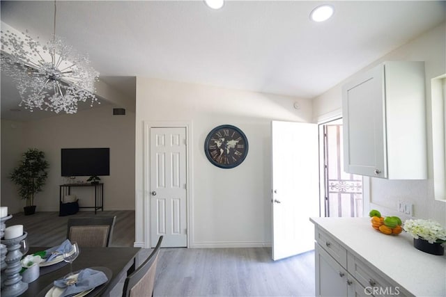 kitchen with pendant lighting, a notable chandelier, light hardwood / wood-style floors, and white cabinetry