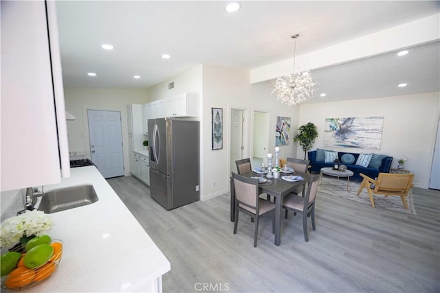 dining space featuring light hardwood / wood-style floors, a notable chandelier, and sink