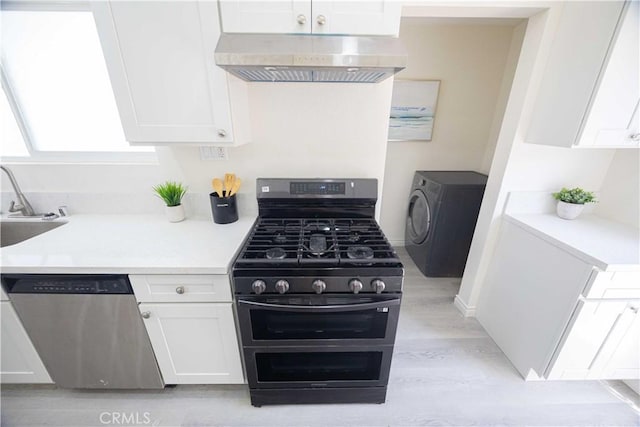 kitchen featuring stainless steel appliances, wall chimney range hood, light hardwood / wood-style floors, washer / dryer, and white cabinets