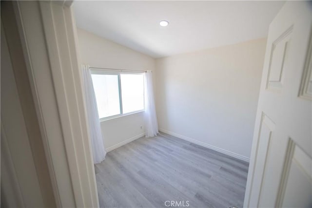 empty room featuring light hardwood / wood-style floors and vaulted ceiling