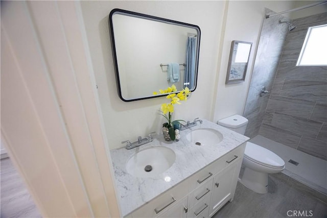 bathroom featuring tiled shower, toilet, vanity, and hardwood / wood-style flooring