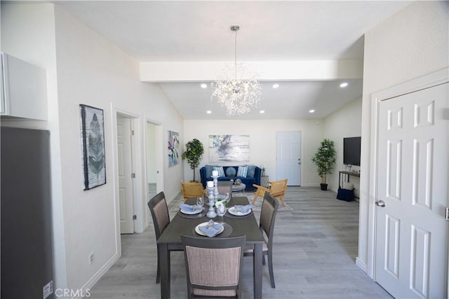 dining area with lofted ceiling with beams, an inviting chandelier, and light hardwood / wood-style flooring