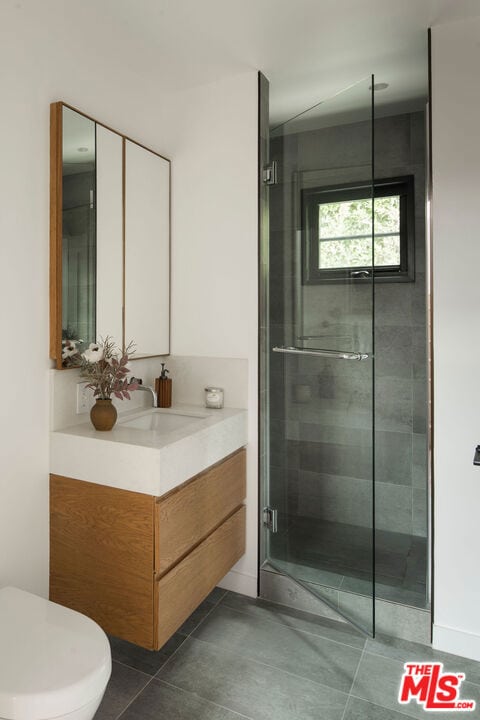 bathroom with tile patterned floors, vanity, an enclosed shower, and toilet