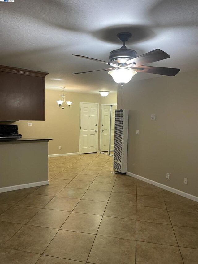 spare room with ceiling fan with notable chandelier and light tile patterned floors